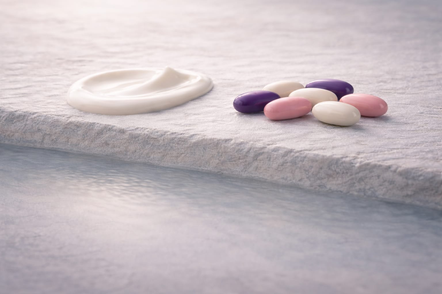 aevora-delivery-controlled-uptake-integrated-system Two refined cream textures—one white and one soft beige—partially absorbed into a cool mineral surface beside opaque deep purple, pink and white capsules, representing controlled delivery and integrated uptake within the Aevora system.